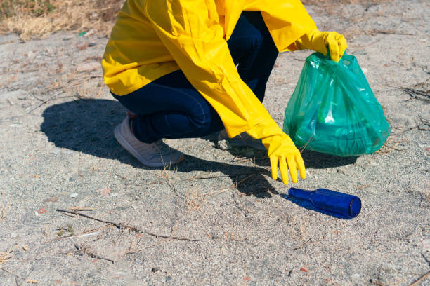 istock Woman in a raincoat picking up garbage in a park 1316147255