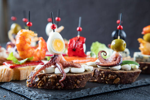 sándwiches mediterráneos tradicionales - tapas españolas que consisten en pulpo con tentáculos, huevo de codorniz, aceituna verde, queso crema - vista lateral de un conjunto de tapas en el bar - spanish cuisine fotografías e imágenes de stock