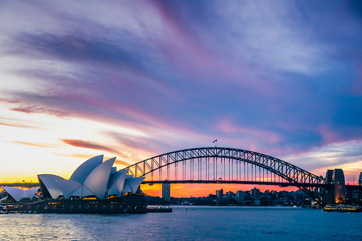 A dramatic sunset sky over the Sydney Harbour Bridge and Sydney Opera House, photo taken from the popular tourist and photography viewpoint of Mrs Macquarie's Chair on Sydney Harbour, New South Wales, Australia, April 20th 2021.