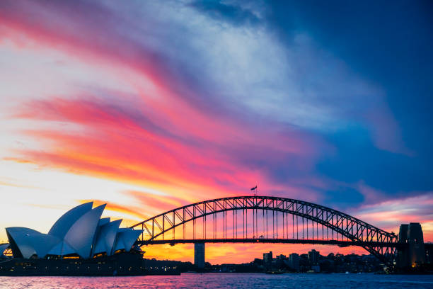 Sydney Opera House and Sydney Harbour Bridge at sunset, New South Wales, Australia on 20th April 2021. A dramatic sunset sky over the Sydney Harbour Bridge and Sydney Opera House, photo taken from the popular tourist and photography viewpoint of Mrs Macquarie's Chair on Sydney Harbour, New South Wales, Australia, April 20th 2021. sydney sunset stock pictures, royalty-free photos & images