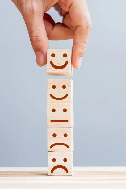 Photo of Hand holding smile face symbol on wooden cube blocks. Emotion, Service rating, ranking, customer review, satisfaction and feedback concept