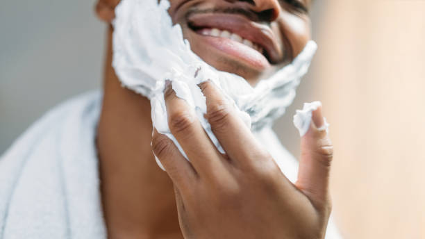 hombre africano de cuidado facial masculino aplicando espuma de afeitar - male towel men human face fotografías e imágenes de stock