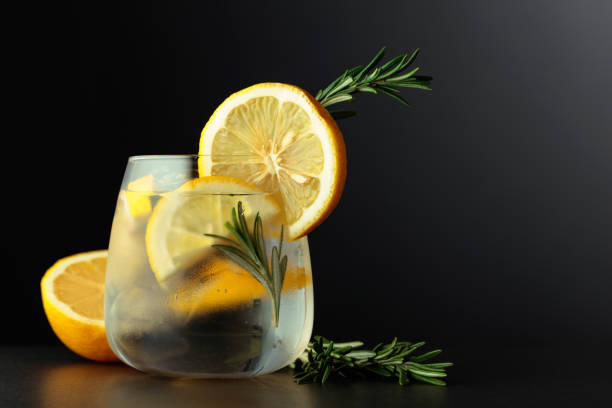 cocktail gin tonic mit zitronenscheiben und zweigen rosmarin auf schwarzem hintergrund. - glass ice tonic water frozen stock-fotos und bilder