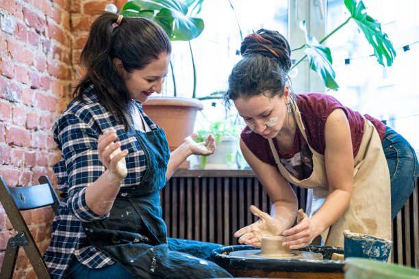 istock Two young women, instructor, and student, doing pottery using a pottery wheel on a workshop. 1316172682
