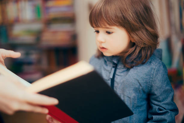 istock Toddler Girl Looking at a Book in a Library 1316173430