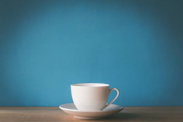 istock White coffee cup on wooden desk with blue background 1316174670