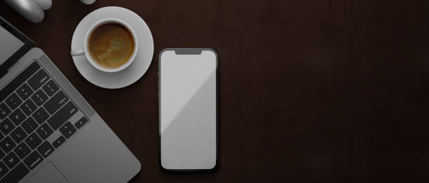 istock 3D rendering, smartphone with mock-up screen on brown leather background with laptop and coffee cup, top view 1316176282