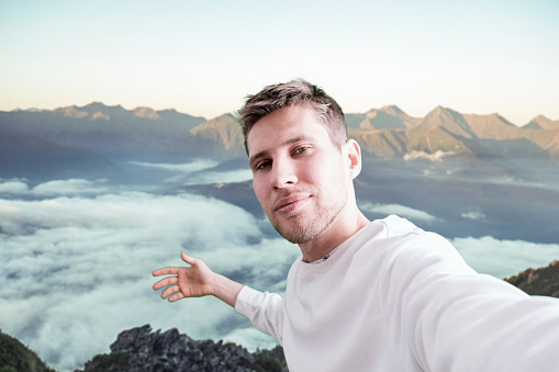 young man hiking the mountain, making a self portrait on the mountain peak