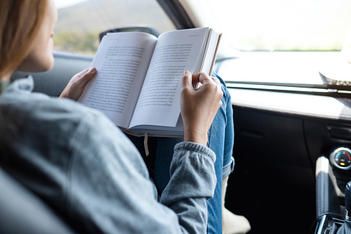 A woman reading book while riding the car
