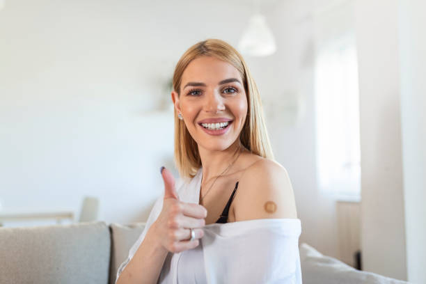 istock Vaccinated young Woman Gesturing Thumbs-Up Approving Vaccination, home Background 1316183890