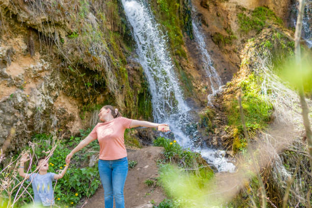 istock Mother with son enjoying the mountain, standing under the waterfall 1316186403