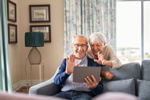 szczęśliwa starsza para wykonująca rozmowę wideo w domu - couple laptop computer digital tablet zdjęcia i obrazy z banku zdjęć