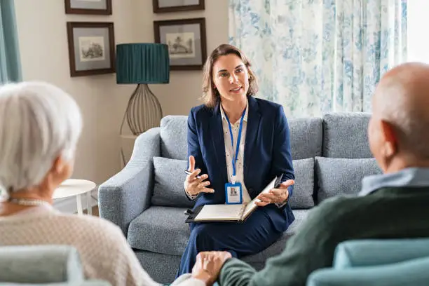 Photo of Social worker talking to senior couple at home