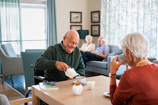 Hombre mayor bebiendo té caliente con su esposa en la comunidad de jubilados photo