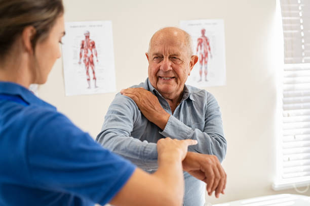 fisioterapista che lavora con un paziente anziano in clinica - senior male foto e immagini stock