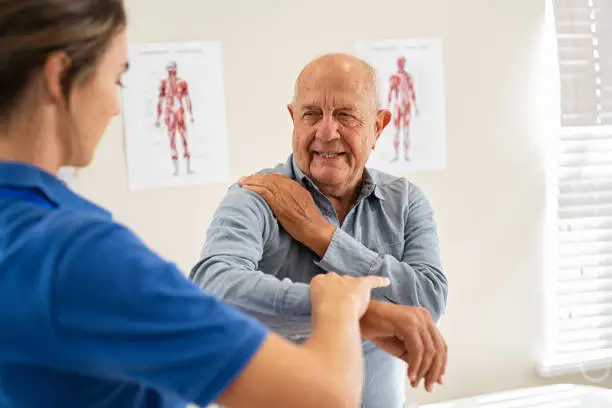 Photo of Physiotherapist working with senior patient in clinic