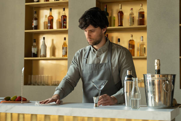 istock Man bartender standing at bar counter wiping table cheerful. Bartender in the workplace 1316203383