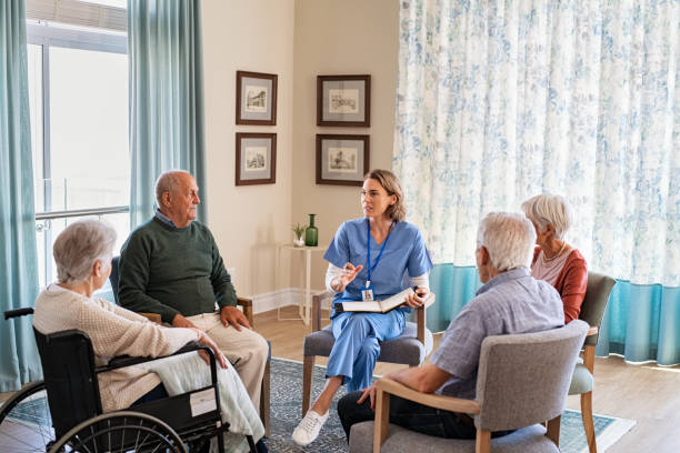 Nurse talking to senior people during group therapy Group of senior people listening to young nurse. Psychological support group for elderly and lonely people in a community centre. Group therapy in session sitting in a circle in a nursing home facility."r group therapy stock pictures, royalty-free photos & images