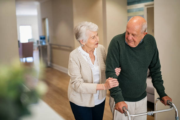 장애가있는 남편이 병원에서 걷는 것을 돕는 노인 여성 - residential care 이미지 뉴스 사진 이미지