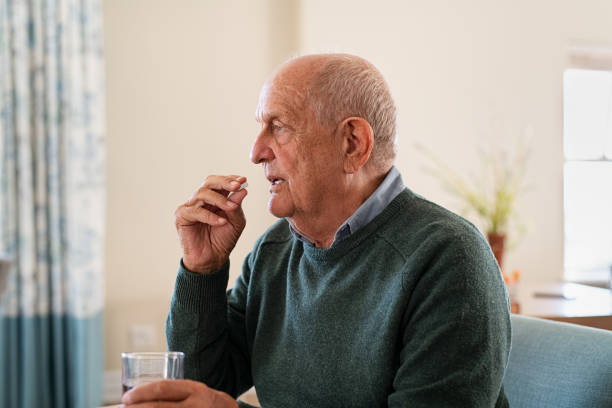vieil homme aîné prenant la pillule de médecine - prozac photos et images de collection