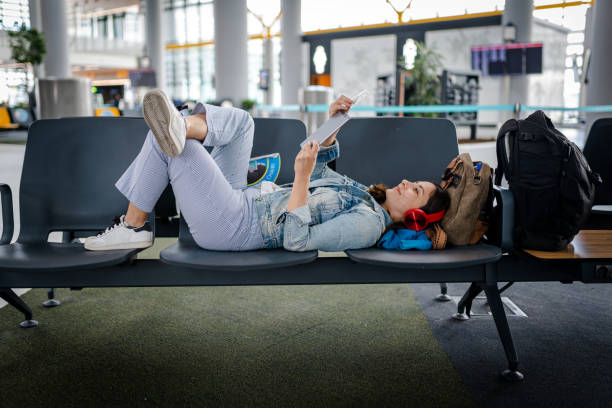 Young Woman waiting for delayed flight and reading digital book on chairs Young Woman waiting for delayed flight and reading digital book on chairs delayed sign photos stock pictures, royalty-free photos & images