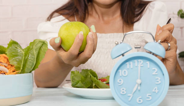 istock Selective focus of green apple in woman hand as Intermittent  fast program on the table background 1316209340