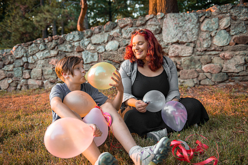Siblings seating on a grass and having fun with balloons
