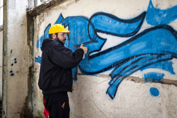 street artist is spraying graffiti on the wall - graffiti men wall street art imagens e fotografias de stock