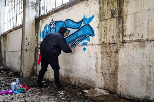 Street artist is spraying graffiti on the wall