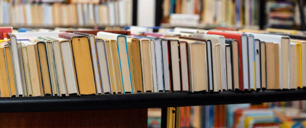 Row of many old used books displayed at local antiquarian bookshop, wide photo focus on right side Row of many old used books displayed at local antiquarian bookshop, wide photo focus on right side textbook stock pictures, royalty-free photos & images