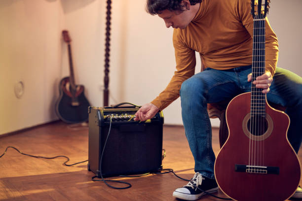 male musician playing acoustic guitar on the amplifier in retro vintage room. - fingerstyle imagens e fotografias de stock