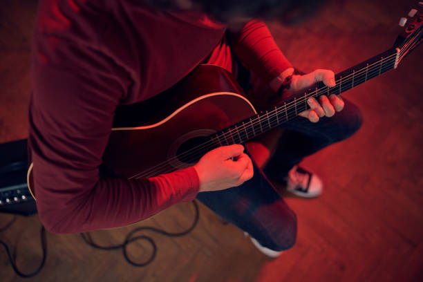 male musician playing acoustic guitar on the amplifier in retro vintage room. - fingerstyle imagens e fotografias de stock