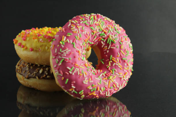 istock Berliner doughnuts with icing pink yellow lie stops and pink bright stands on a black background with room for text 1316217977