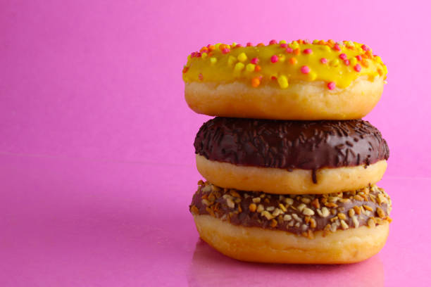istock Sweet still life donut berliner close-up at the back lie a stack of three doughnut chocolate pink yellow on a bright pink fuchsia background with a place for text and with a cpixpe for a cafe for tablecloths for glue 1316219440