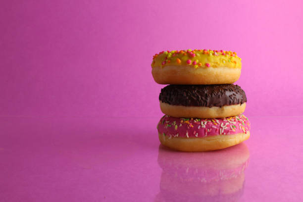 istock three Berliners donut pink yellow chocolate with a sprinkle on a pink background leit stack on top of each other with a place for text and with a copyspace 1316219453
