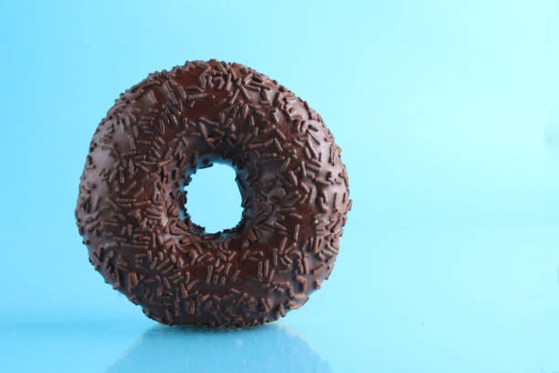 istock Berliner donut pink chocolate lies stands on a blue bright background with a place to text a copy of the still life for the kitchen breakfast sweet meal 1316219528