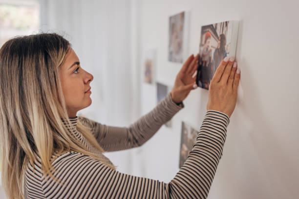 istock Woman decorating her wall with photographs 1316222143