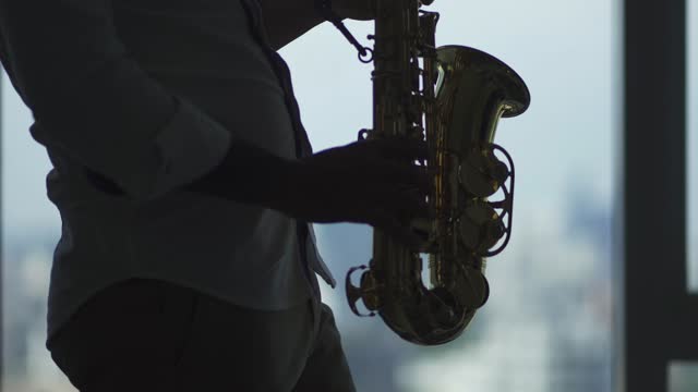 in silhouette lifehack asian active senior man artist enjoying playing saxophone in living room