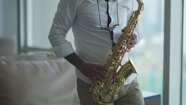 asian active senior man artist enjoying playing saxophone living room