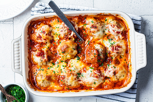 Baked cheesy meatballs casserole with tomato sauce in the oven dish.