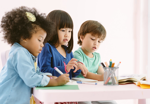 Grupo de diversidad niños dibujando y pintando con crayón junto con diversión en la clase de arte en el jardín de infantes. Preescolar internacional, concepto de educación. photo
