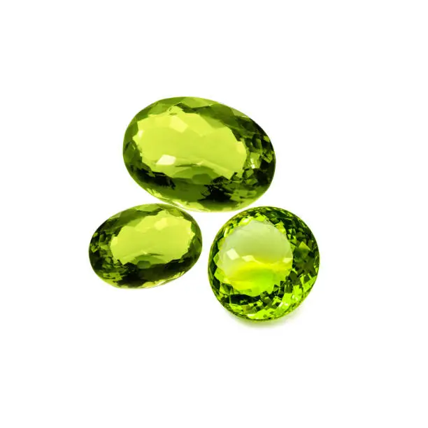 Three peridot or chrysolite gems on a white background
