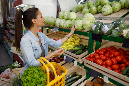 Beautiful young woman buying fresh vegetables at the supermarket
