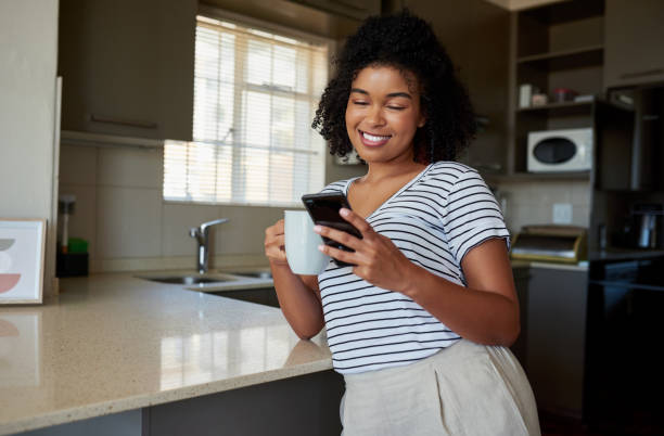 istock Shot of a woman drinking coffee while using her cellphone at home 1316229374