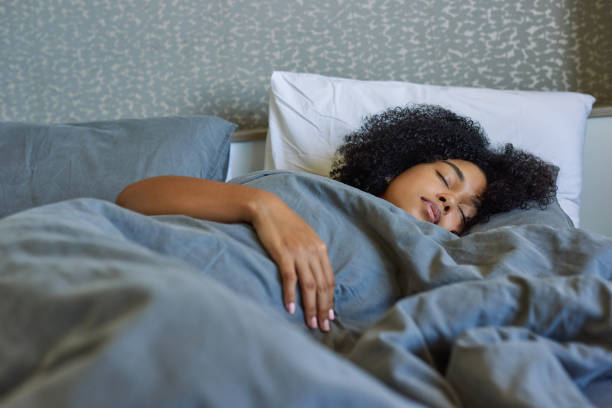 shot of a young woman sleeping in her bed at home - deitando imagens e fotografias de stock