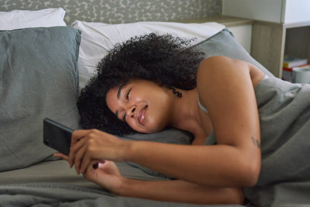 istock Shot of a young woman using her cellphone while lying in her bed 1316229407