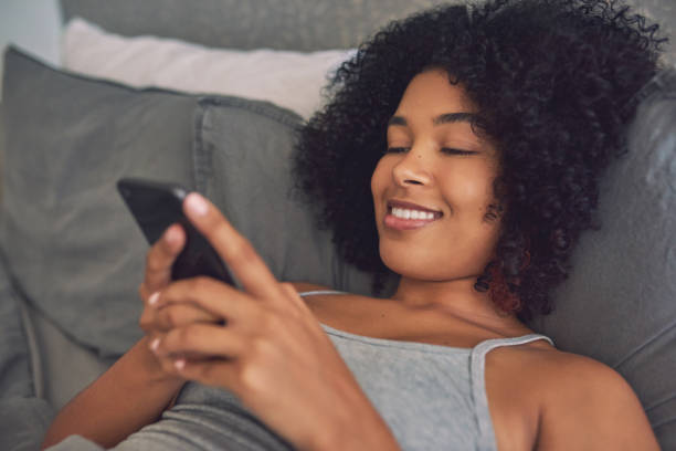 istock Shot of a young woman using her cellphone while lying in her bed 1316229412