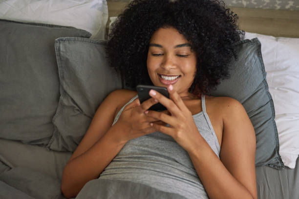 istock Shot of a young woman using her cellphone while lying in her bed 1316229419