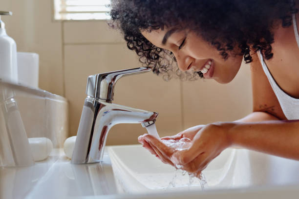 Shot of a beautiful young woman washing her face in the bathroom Let's get this day started woman washing face stock pictures, royalty-free photos & images