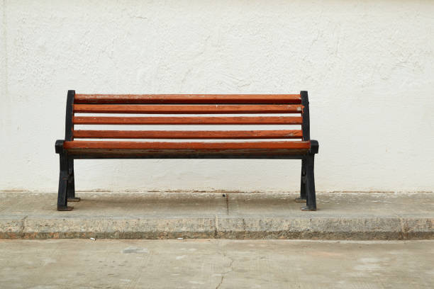 istock a brown street bench against a white wall 1316232788